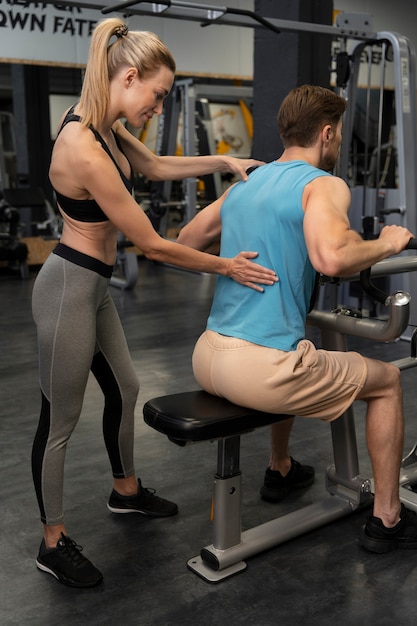 Entraîneur aidant le débutant au gymnase