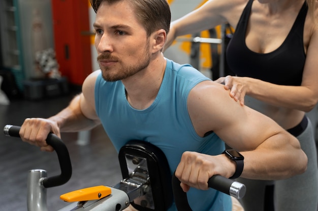 Photo gratuite entraîneur aidant le débutant au gymnase