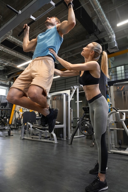 Photo gratuite entraîneur aidant le débutant au gymnase