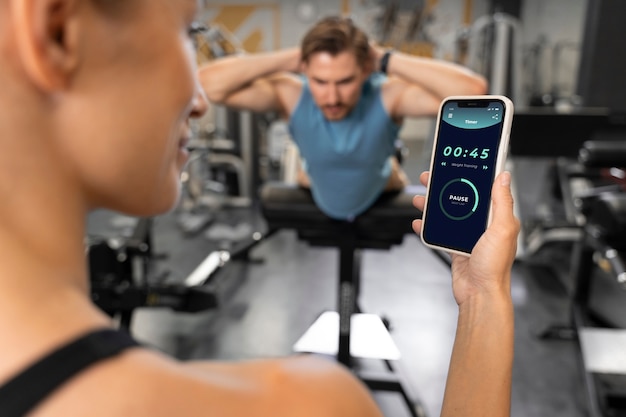 Photo gratuite entraîneur aidant le débutant au gymnase