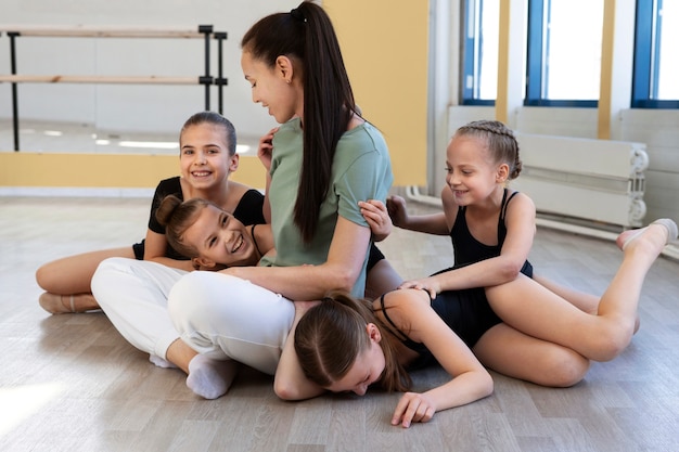 Entraîneur de ballet féminin posant avec des filles au gymnase