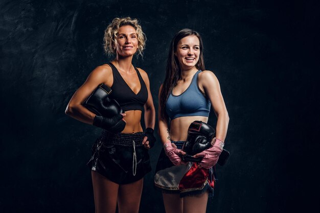 Un entraîneur de boxe expérimenté et son jeune étudiant posent pour un photographe dans un studio photo sombre.