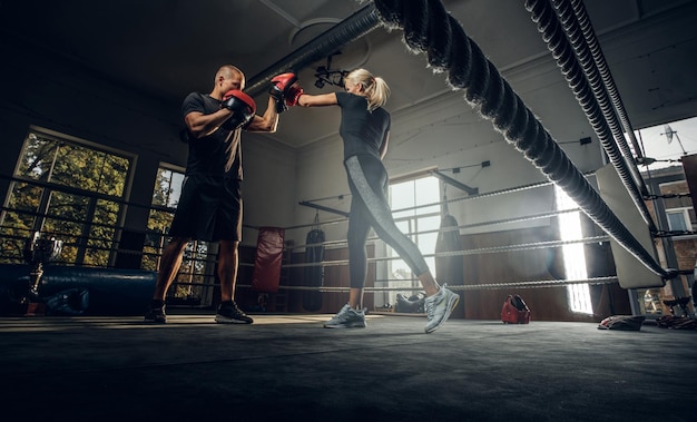 L'entraîneur de boxe et son nouvel élève s'affrontent sur le ring avec des gants de boxe.