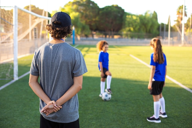 Entraîneur de football aidant les enfants vue de dos
