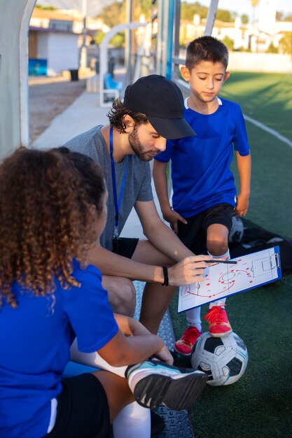 Entraîneur de football enseignant la vue latérale des enfants