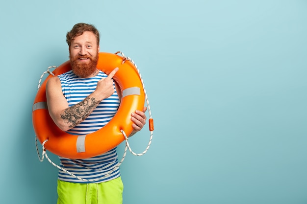 Photo gratuite un entraîneur ou un instructeur de natation joyeux porte une bouée de sauvetage sur le corps, donne des leçons de natation en toute sécurité