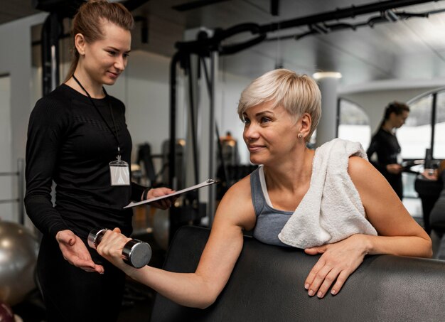 Entraîneur personnel féminin et son client à l'aide d'haltères