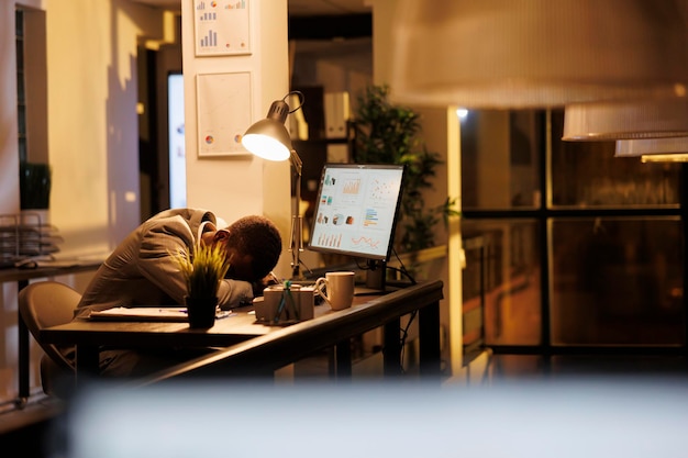 Photo gratuite un entrepreneur fatigué et épuisé dormant sur son bureau dans un bureau de start-up.