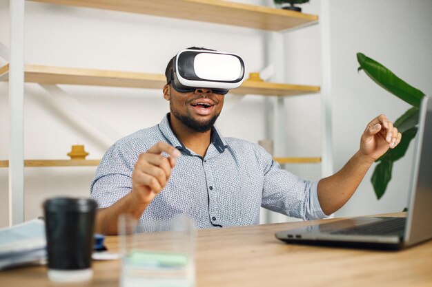 Entrepreneur noir assis au bureau et utilisant des lunettes de réalité virtuelle