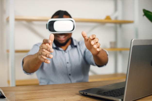 Photo gratuite entrepreneur noir assis au bureau et utilisant des lunettes de réalité virtuelle