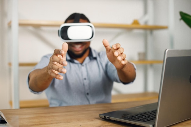 Entrepreneur noir assis au bureau et utilisant des lunettes de réalité virtuelle