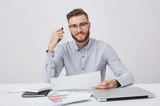 Un entrepreneur professionnel réussi tient du papier et un stylo, lit attentivement le contrat