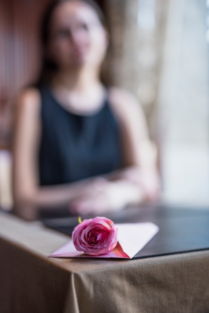 Photo gratuite enveloppe et fleur sur la table près de la femme