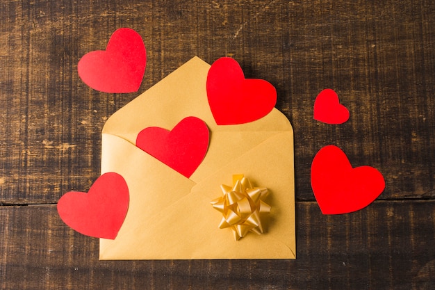 Enveloppe ouverte jaune avec coeur rouge et archet sur planche de bois texturée