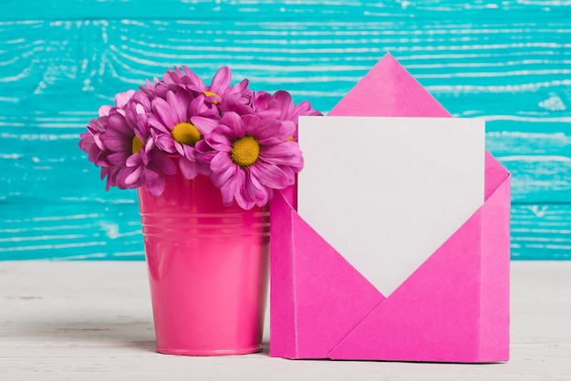 enveloppe rose avec un morceau de papier et de fleurs violettes décoratives