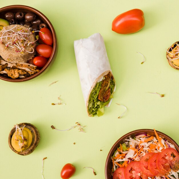 Enveloppement au burrito avec du riz; champignons farcis; salade et dessert sur fond vert
