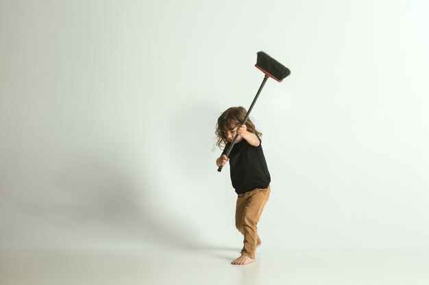 Envie d'être utile comme un père. Petit enfant debout et jouant isolé. Le jeune garçon aux cheveux blonds a l'air ludique et occupé. Concept d'enfance, bonheur, émotions.