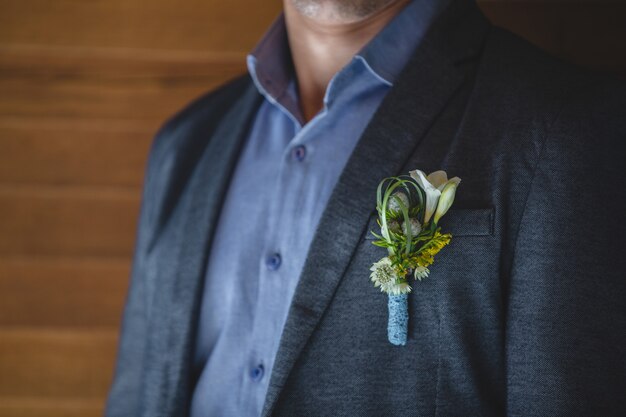 Une épingle de couleur pastel saisonnière fleurit dans la veste d'un homme.