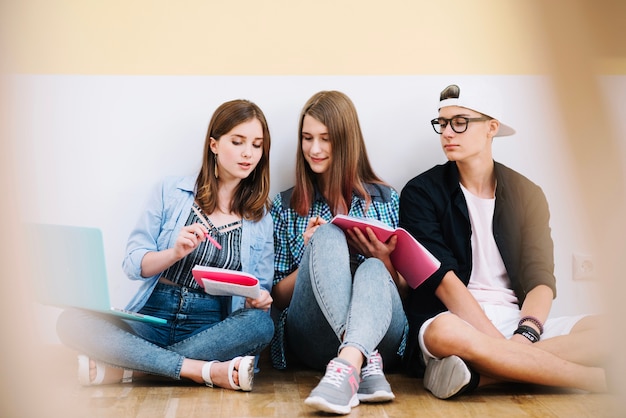 Photo gratuite Équipe d'étudiants posant avec des bloc-notes