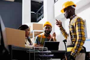 Photo gratuite Équipe de gestionnaires logistiques afro-américains discutant de la distribution des marchandises à la réception de l'entrepôt. les hommes et les femmes du bureau de poste planifient l'approvisionnement en stock tout en discutant au comptoir