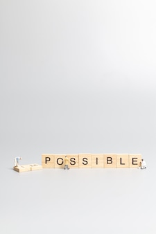 Équipe de travailleurs de personnes miniatures sur mot impossible dans les lettres de l'alphabet en bois avec préfixe un barré, laissant le mot possible