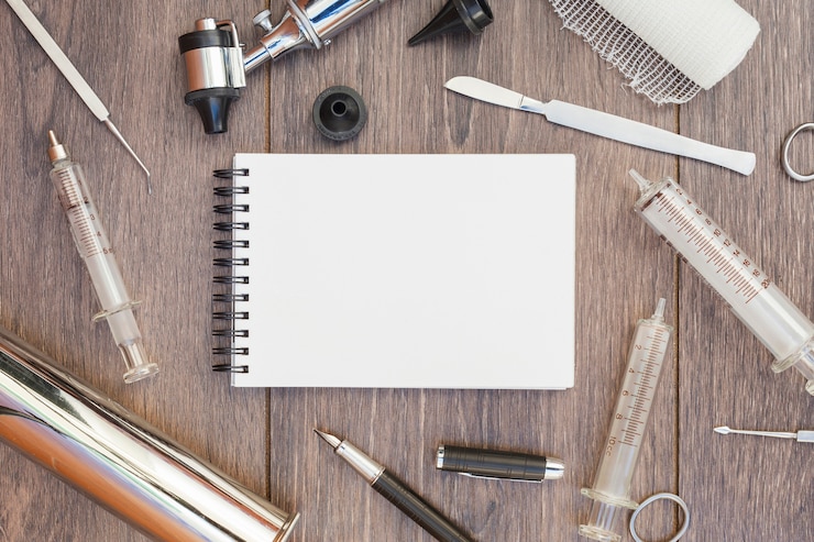Photo gratuit l&#39;équipement médical est entouré autour du bloc-notes en spirale vierge sur un bureau en bois