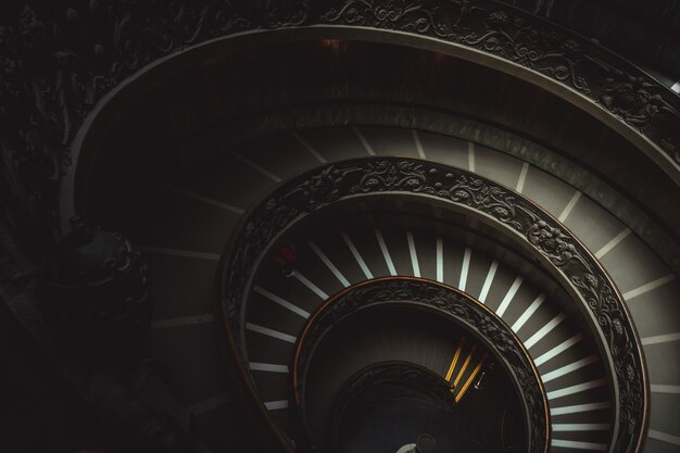 Escalier rond dans un musée du Vatican amenant les visiteurs à regarder des œuvres d'art chrétiennes