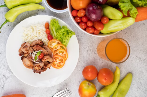 Escalope de porc grillée avec tomates et salade, disposée dans un plat blanc.