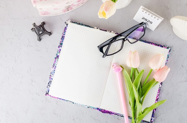 Espace de travail blogger ou indépendant avec tulipes, cahier, horloge et vide