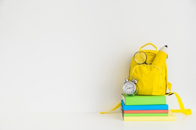 Espace de travail créatif avec sac à dos jaune et cahiers
