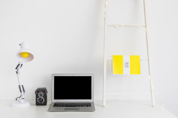 Espace de travail élégant de couleur blanche avec échelle et lampe de bureau