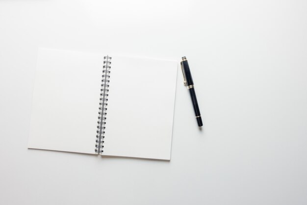 Espace de travail minimal - Photo créative d&#39;une table plate de bureau d&#39;espace de travail avec carnet de croquis et crayon en bois sur fond blanc de copie. Vue de dessus, photographie à plat.