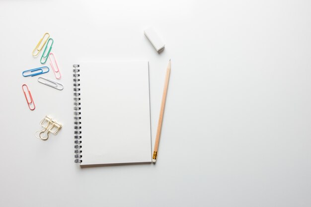 Espace de travail minimal - Photo créative de la table plate du bureau de l&#39;espace de travail avec un carnet de croquis et un crayon en bois sur un fond de copie fond blanc. Vue de dessus, photographie plate.