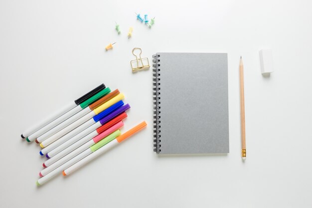 Espace de travail minimal - Photo créative de la table plate du bureau de l&#39;espace de travail avec un carnet de croquis et un crayon en bois sur un fond de copie fond blanc. Vue de dessus, photographie plate.