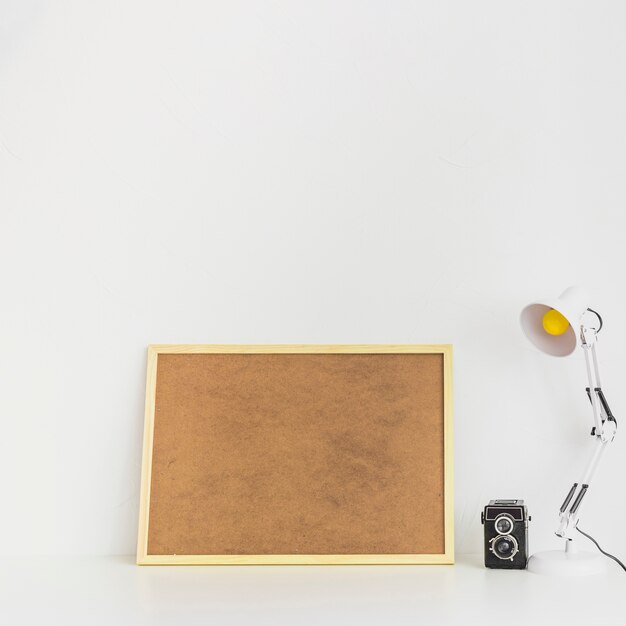 Espace de travail minimaliste avec planche de liège et vieil appareil photo