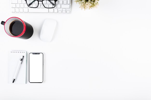 Espace de travail avec une tasse de smartphone et un clavier