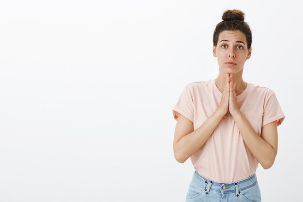 Espoir jeune femme élégante posant contre le mur blanc