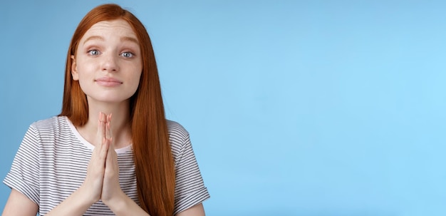 Photo gratuite c'est une fille européenne rousse et mignonne qui demande une faveur. la tasse, les mains ensemble, le geste de la prière, dites s'il vous plaît.