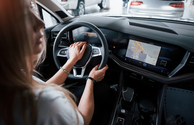 Photo gratuite et c'est parti. fille en voiture moderne dans le salon. le jour à l'intérieur. acheter un véhicule neuf