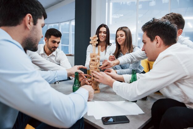 C'est presque une chute. Célébration d'une transaction réussie. Jeunes employés de bureau assis près de la table avec de l'alcool