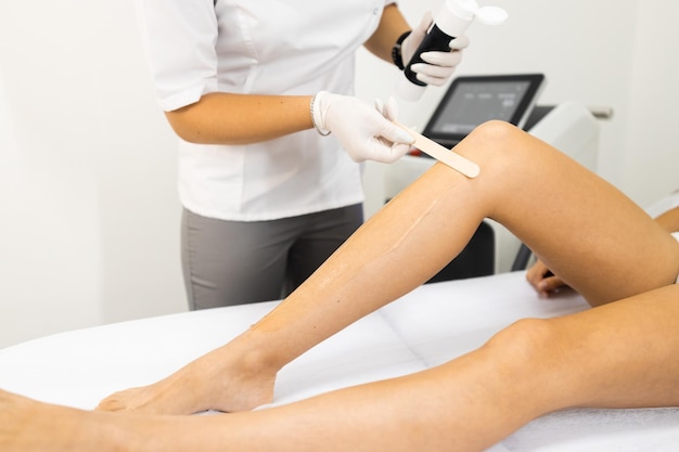 L'esthéticienne applique un gel rafraîchissant spécial pour l'épilation au laser sur la jambe d'une femme