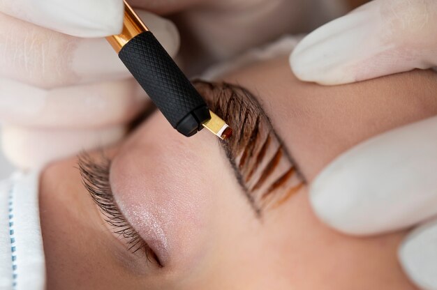 Esthéticienne faisant une procédure de microblading sur les sourcils d'un client