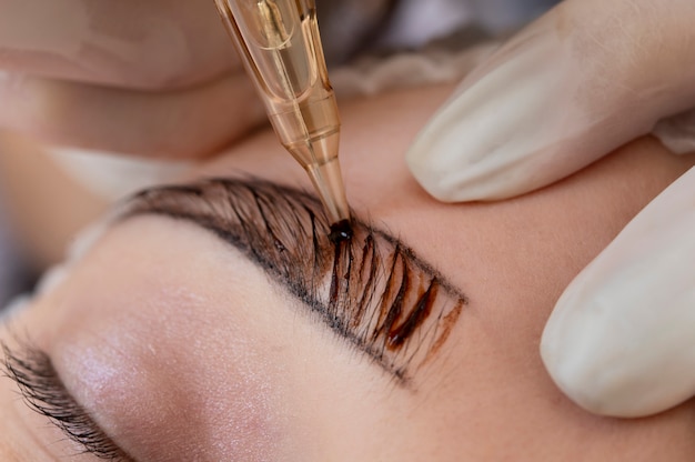 Esthéticienne faisant une procédure de microblading sur les sourcils d'un client