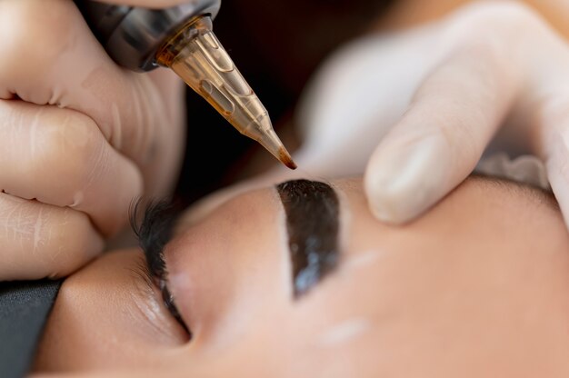 Esthéticienne faisant un traitement de microblading sur les sourcils d'un client