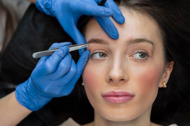 Esthéticienne faisant un traitement des sourcils pour sa cliente