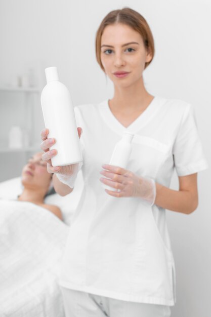 Esthéticienne avec lotion pour cliente