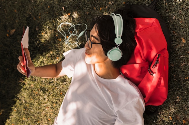 Ethnique adolescent couché sur le sol avec un livre