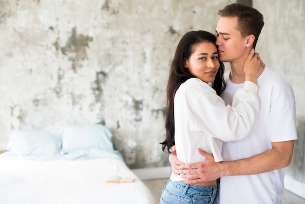 Photo gratuite ethnique femme étreignant son petit ami et regardant la caméra