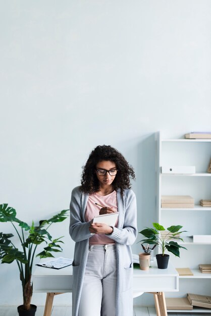 Ethnique jeune femme écrivant dans le presse-papiers