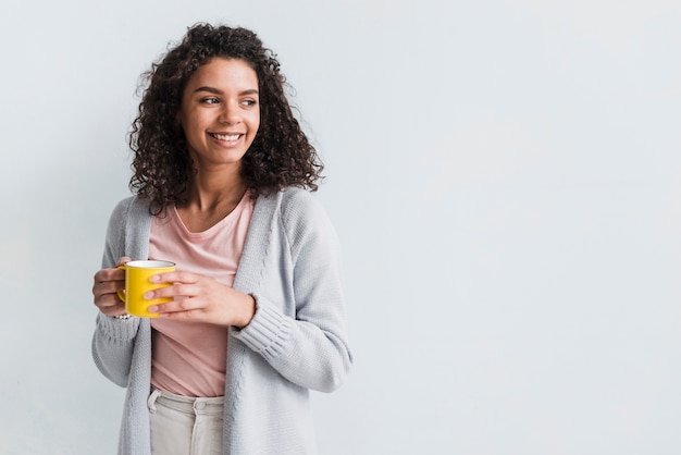 Ethnique jeune femme tenant une tasse sur fond blanc